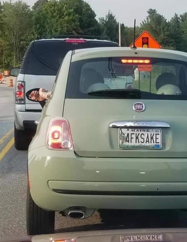 the back end of a green car parked on the side of the road next to another car