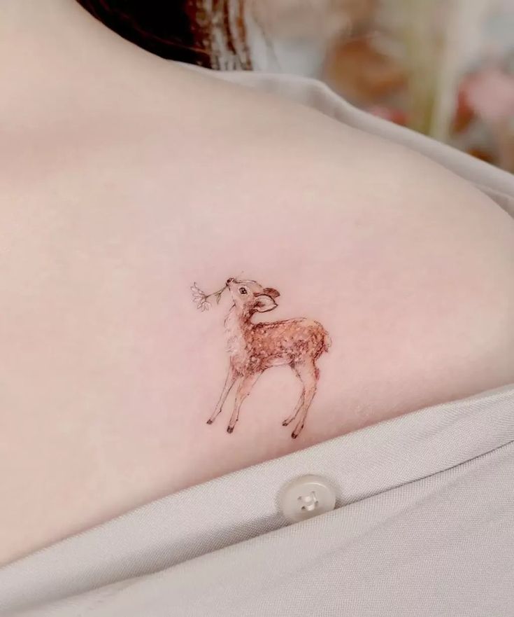 a small deer tattoo on the back of a woman's left shoulder and chest