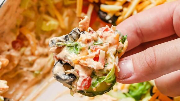 a hand holding a tortilla filled with chicken salad