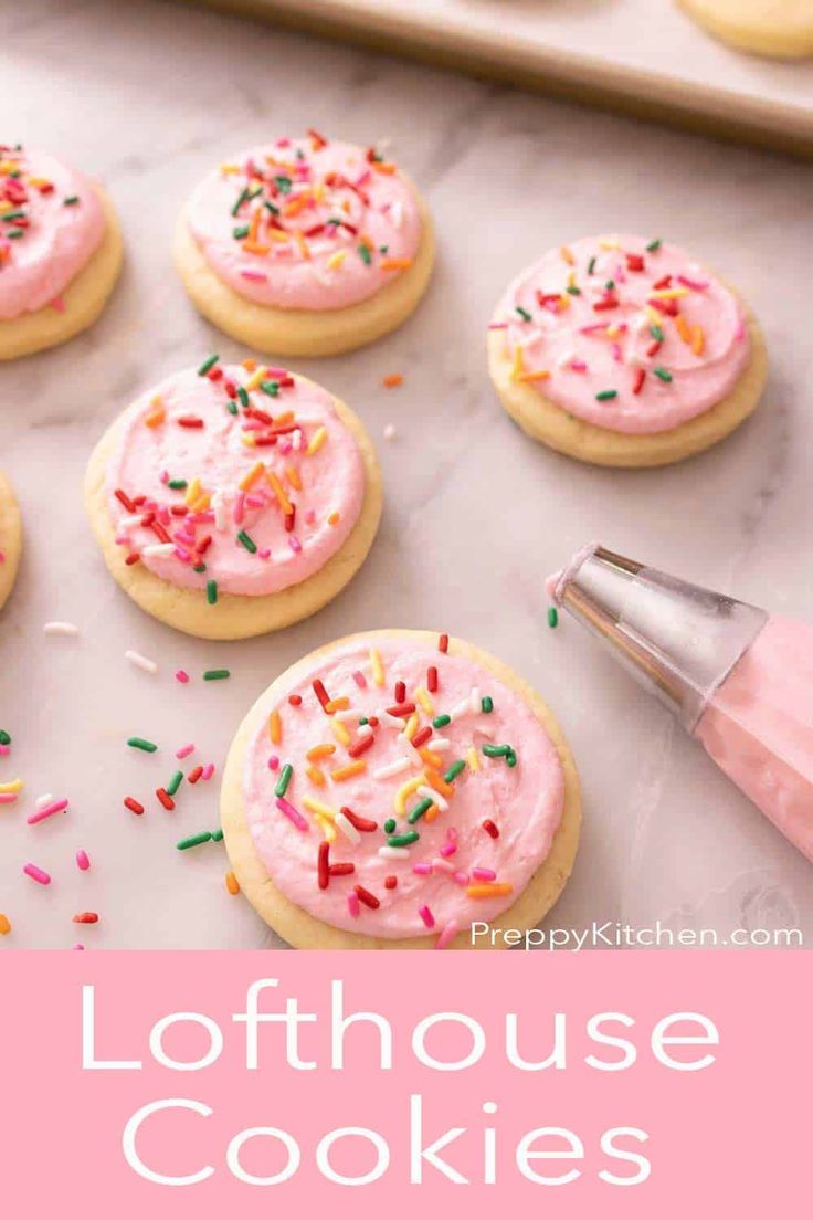 some cookies with pink frosting and sprinkles are on a baking sheet