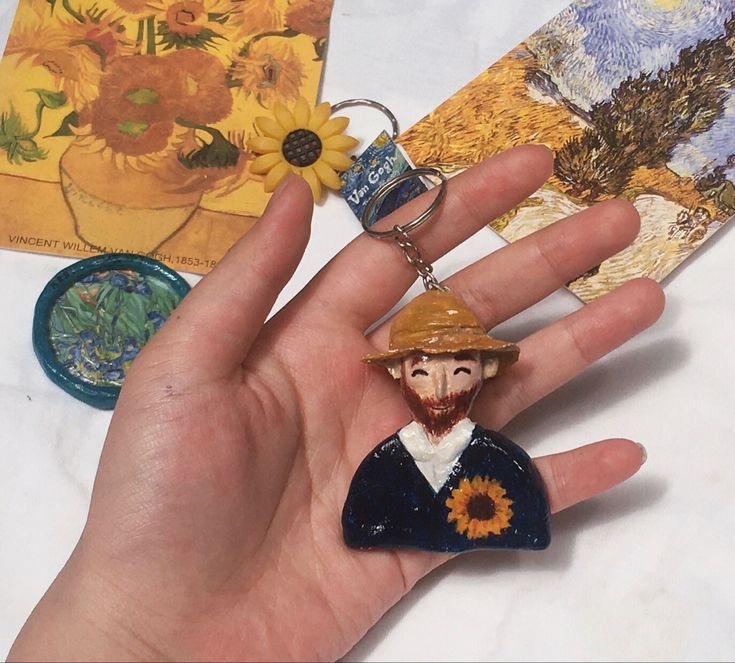 a person's hand holding a small keychain with an image of a man wearing a hat