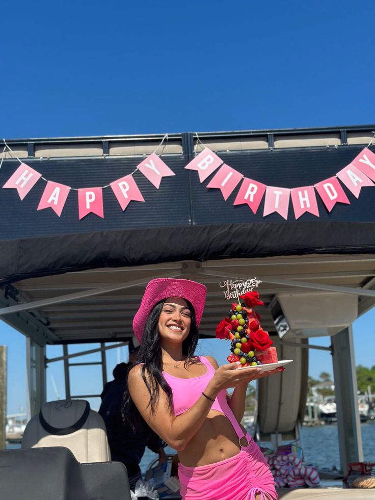 a woman in a pink outfit holding a plate with flowers on it and a sign that says happy birthday