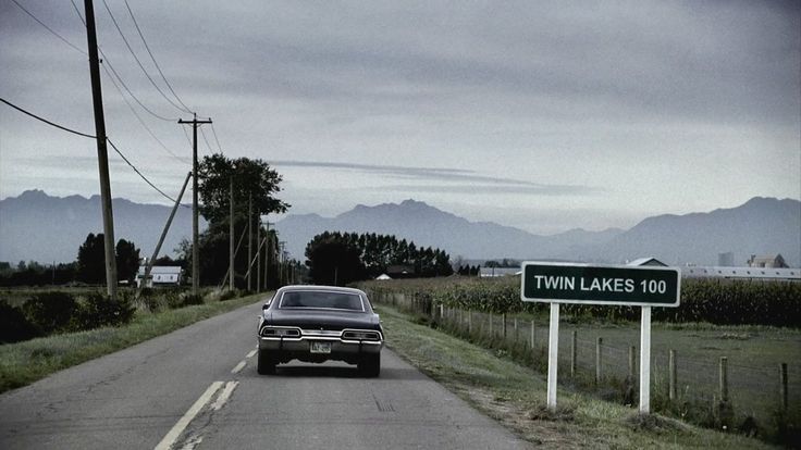 an old car driving down the road with a street sign in front of it that says twin lakes 101