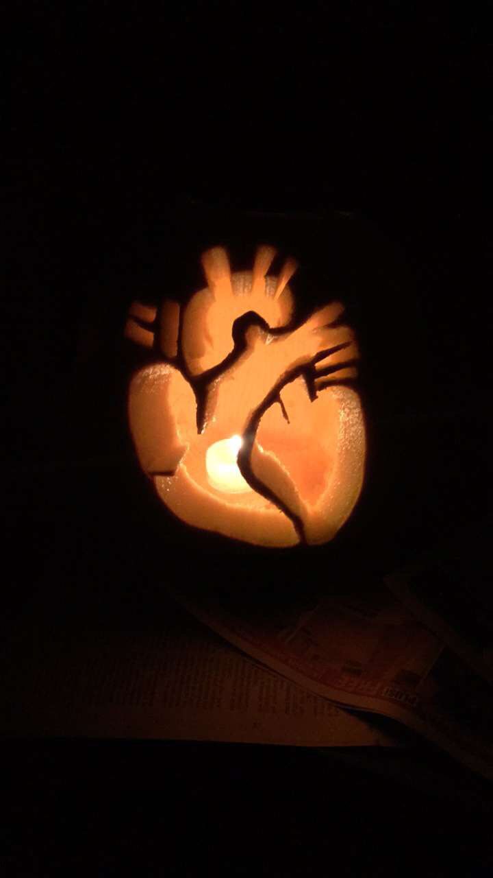 a pumpkin carved to look like a hand holding a baby's foot in the dark