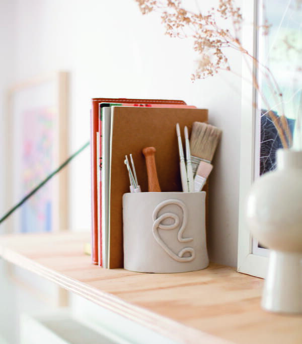 there is a cup with some brushes in it on the shelf next to a mirror