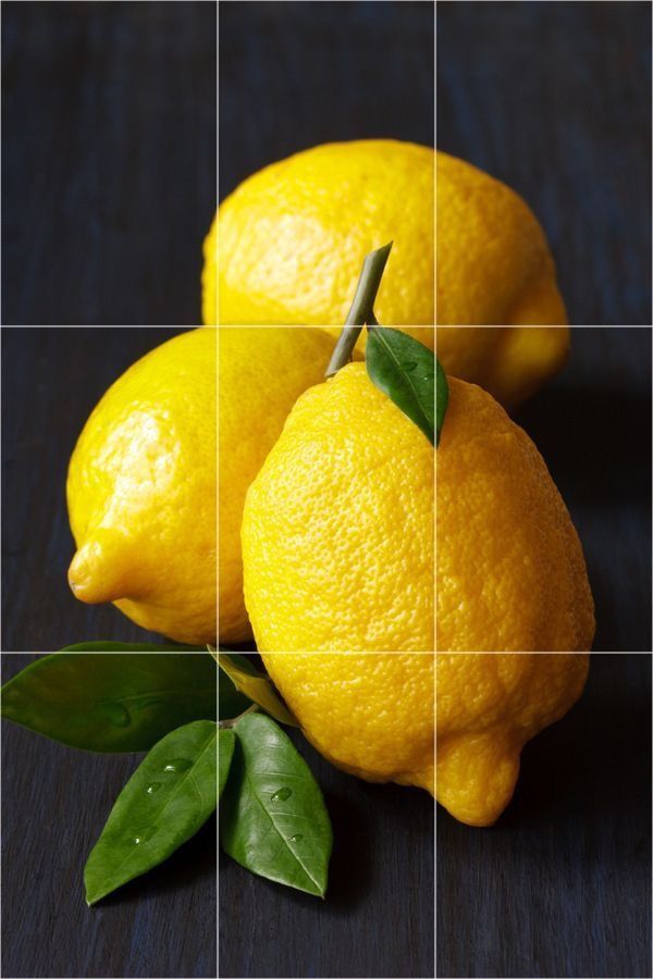 two lemons with green leaves sitting on a table next to each other in front of a grid