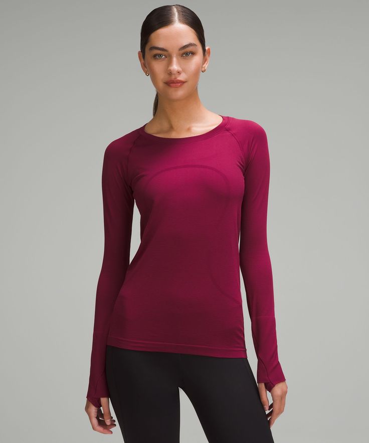 a woman is wearing a maroon top and black leggings with her hands on her hips