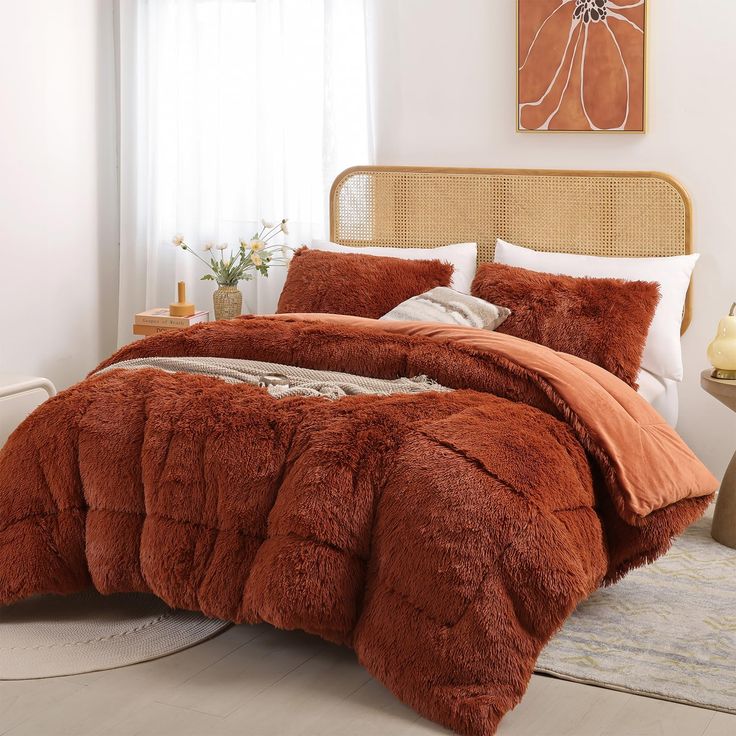 a bed with orange comforter and pillows in a room