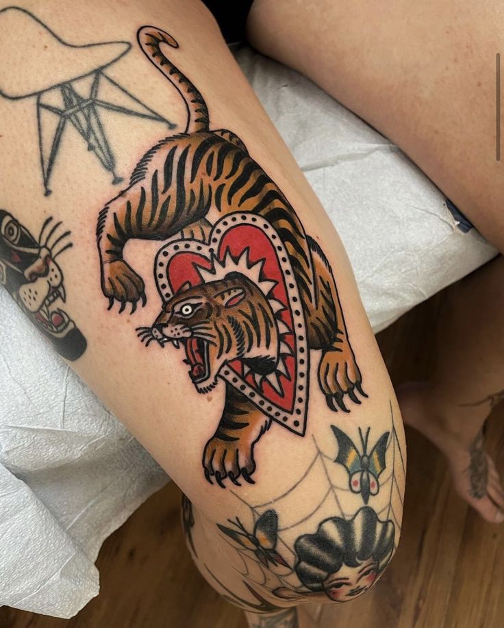 a woman's leg with tattoos on it and a tiger in the middle of her legs