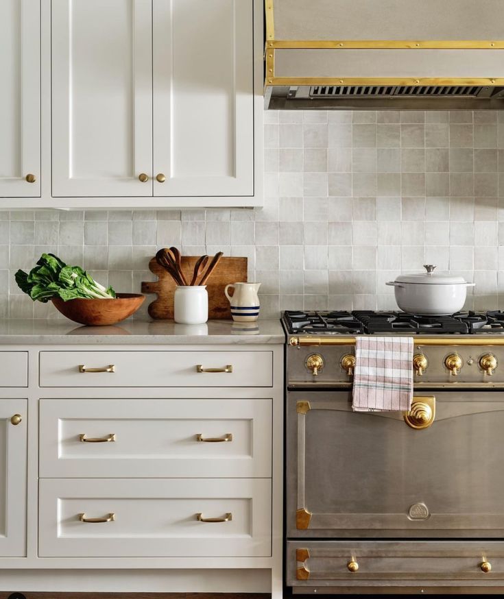 a stove top oven sitting inside of a kitchen next to white cabinets and counter tops