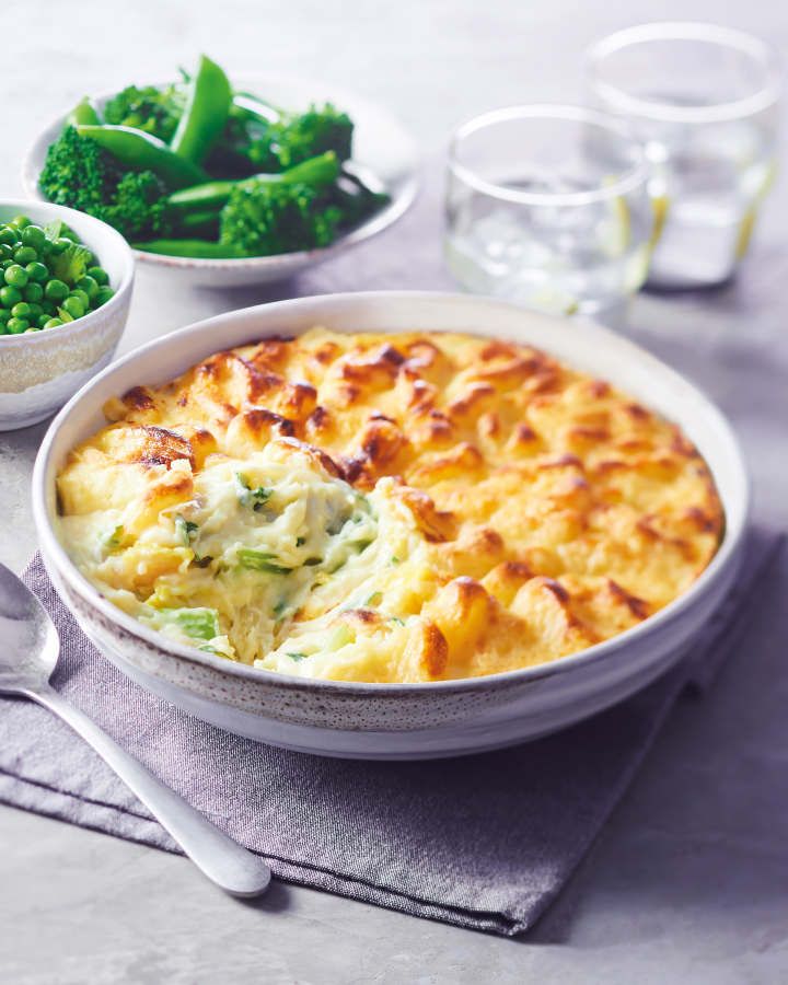 a white bowl filled with food next to broccoli and peas