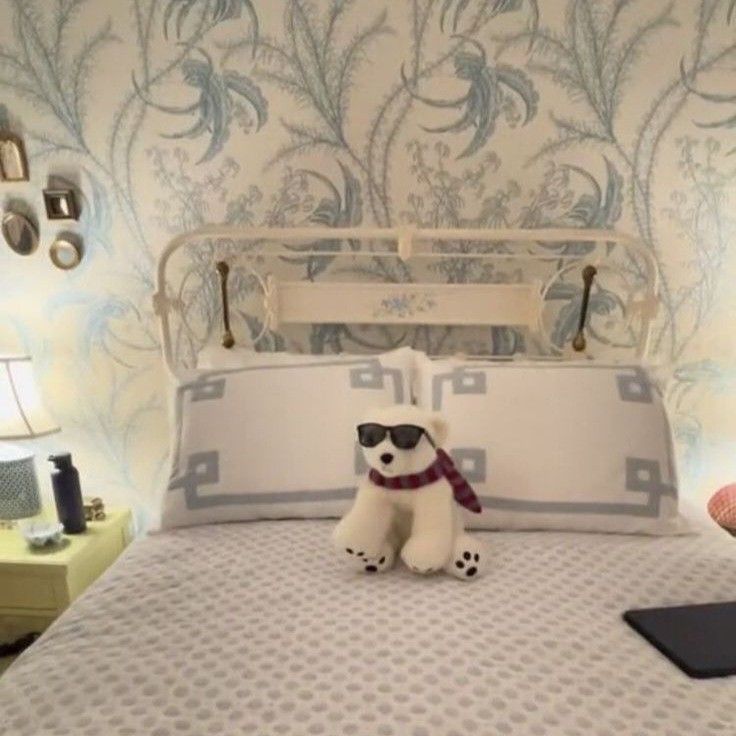 a stuffed dog sitting on top of a bed in a room with blue and white wallpaper