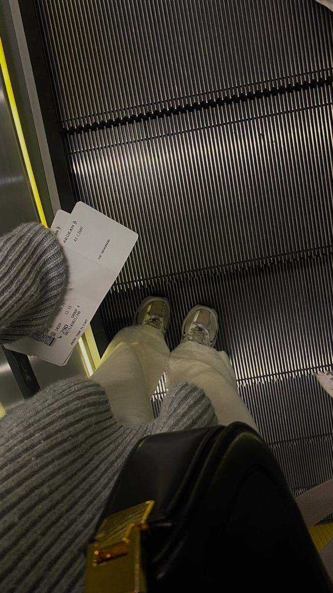 a person with their feet up on an escalator holding a piece of paper