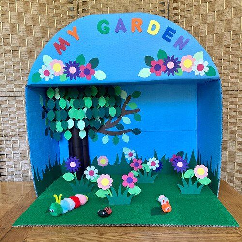 an open cardboard garden with flowers and bugs