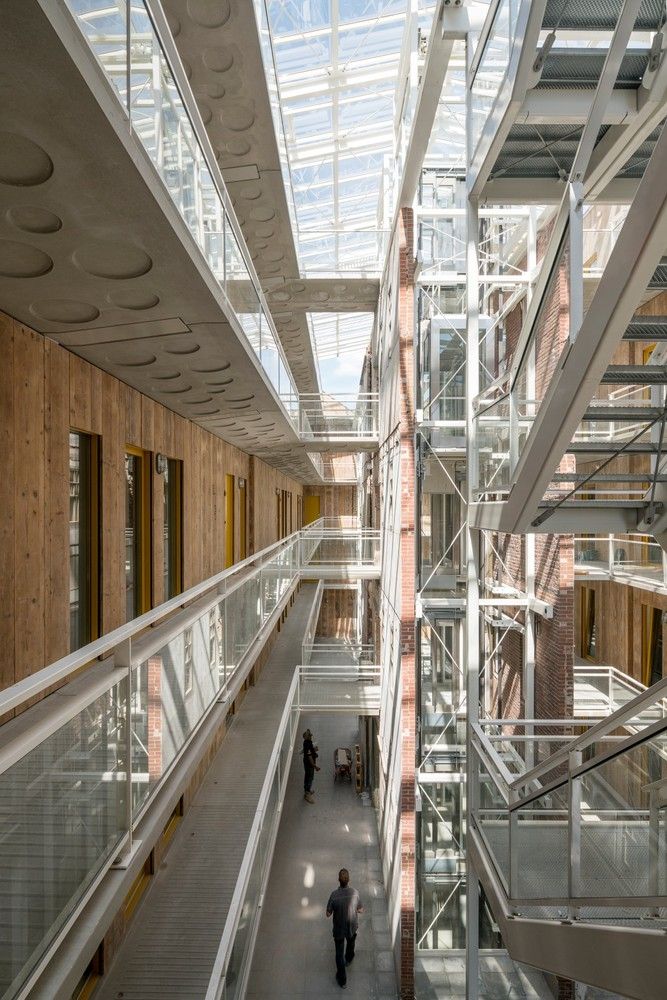 two people are walking up and down the stairs in a large building with glass walls