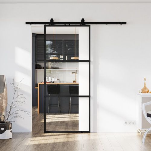 an open living room with white walls and black sliding glass doors that lead into the kitchen