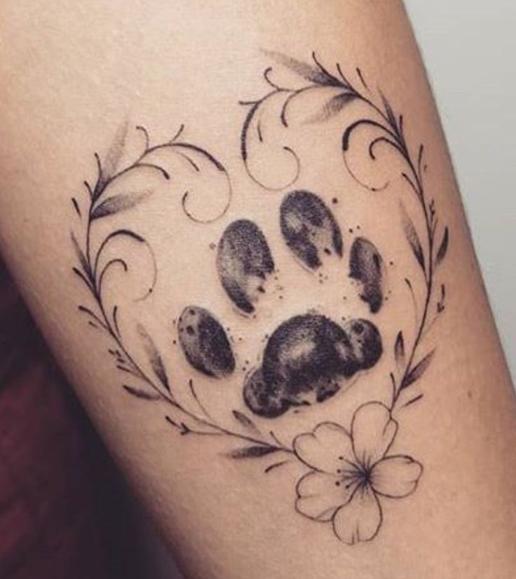 a dog paw tattoo on the thigh with flowers and leaves around it's ankles