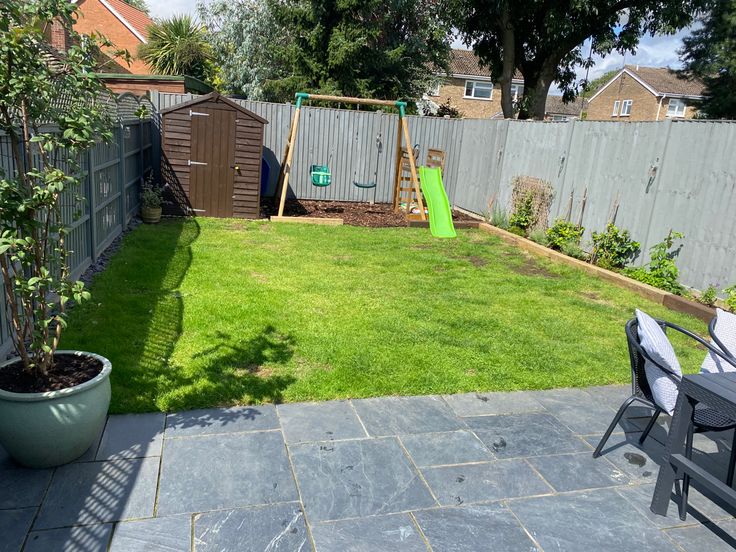 a small backyard with a green slide in the back yard