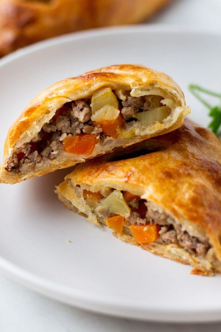 two meat and vegetable pastries on a white plate