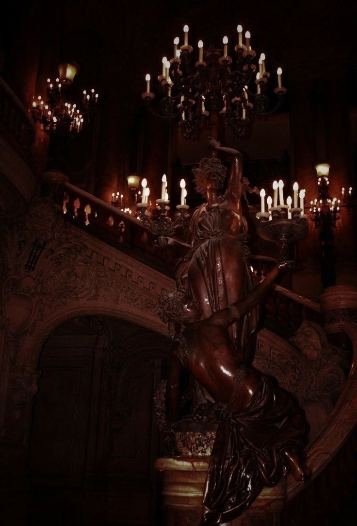 a statue sitting on top of a table next to a chandelier filled with candles