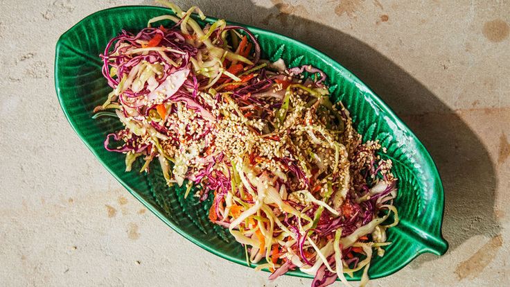 a green plate filled with coleslaw slaw on top of a white table