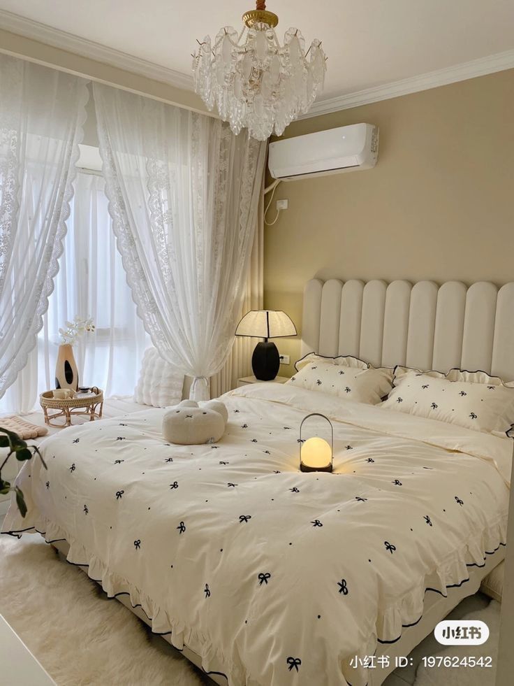 a white bed sitting in a bedroom next to a chandelier above it's headboard