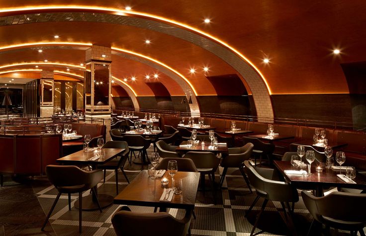 an empty restaurant with checkered flooring and round tables set up for formal dining