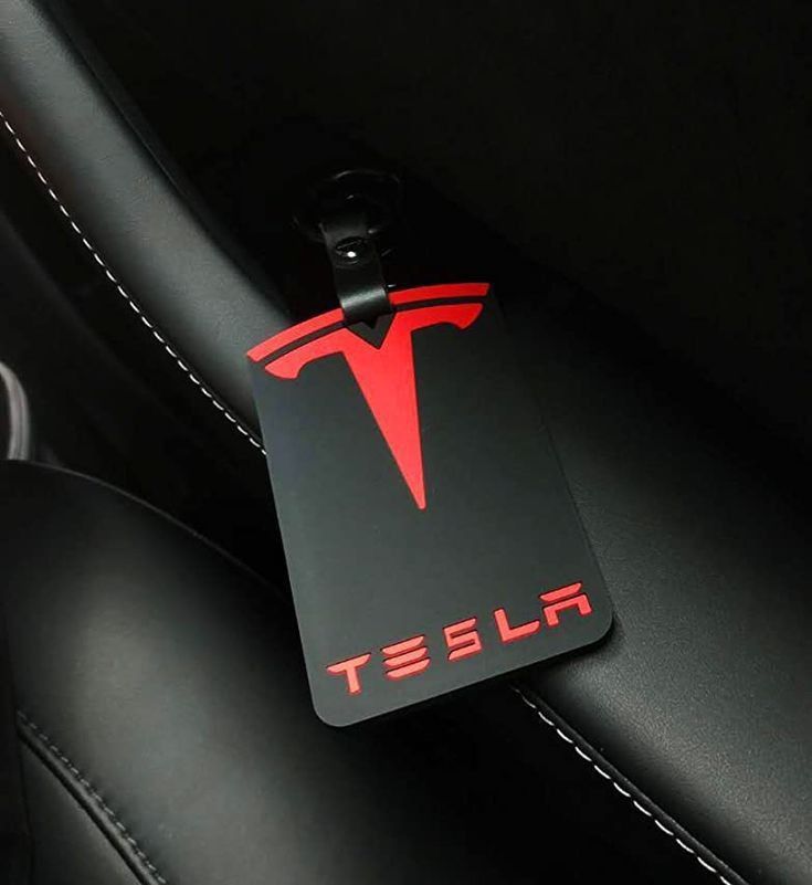 a red tesla logo on the side of a black leather seat in a sports car