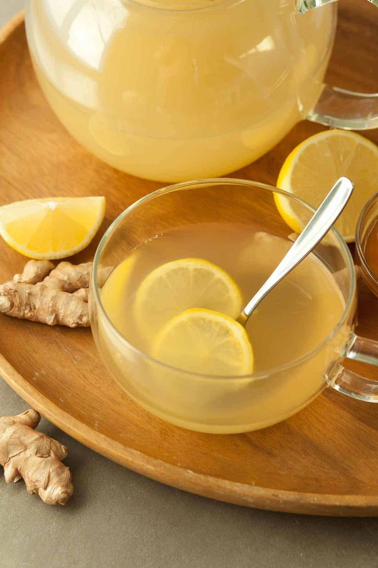 a pitcher of lemonade and some ginger on a wooden tray