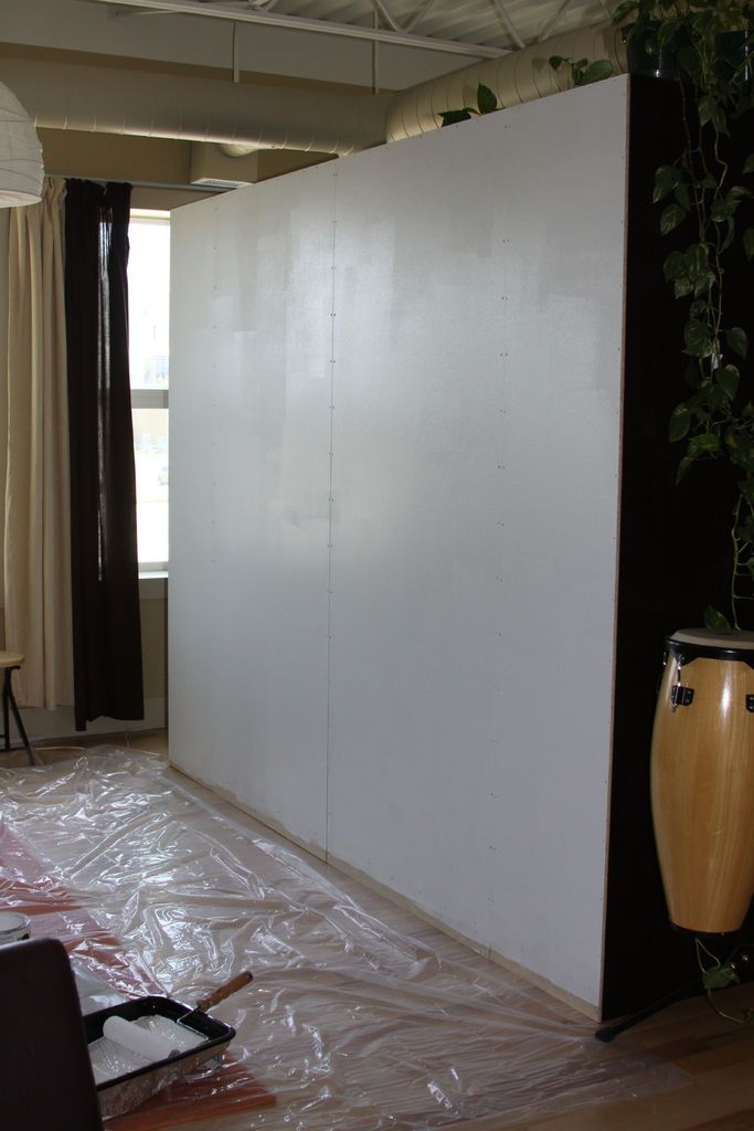 an empty room with a large white wall next to a planter and other items