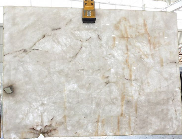 a large marble slab is being worked on by a machine in a building with white walls