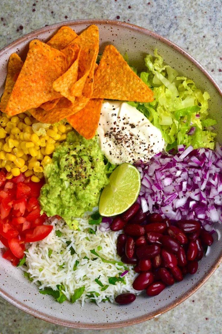 a bowl filled with different types of vegetables and tortilla chips on top of it