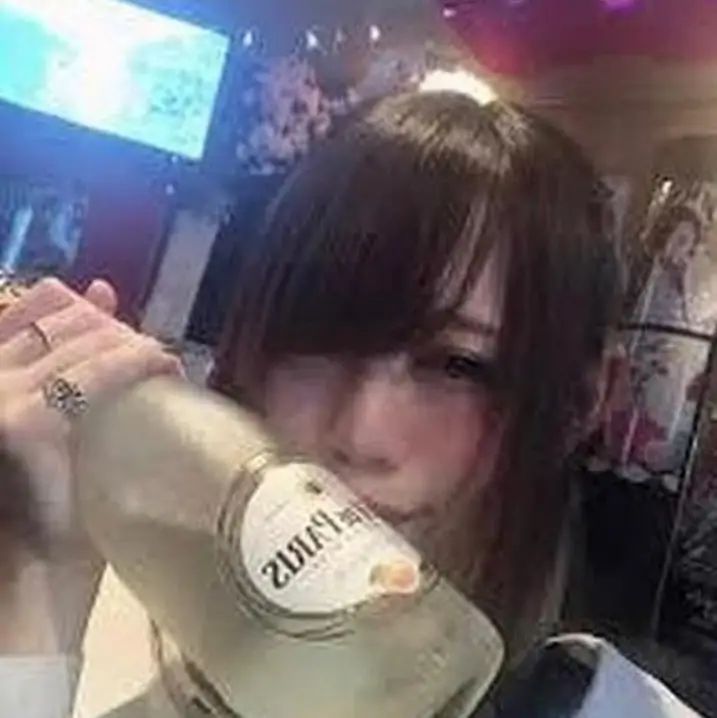 a woman drinking from a bottle in a bar