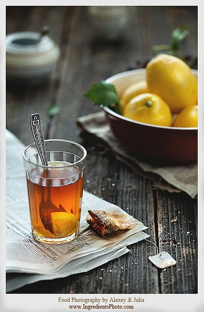 a cup of tea and some lemons on a wooden table with paper napkins