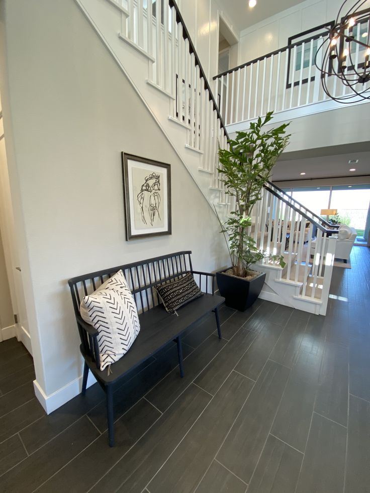 a black bench sitting under a stair case next to a plant