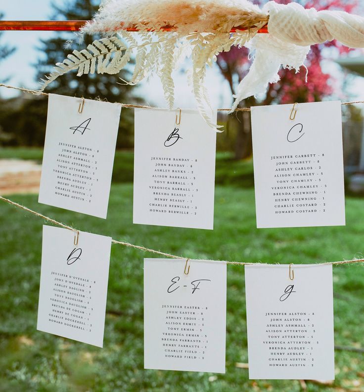 wedding seating cards hung on a line in the grass