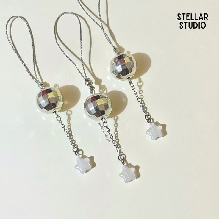 three necklaces are hanging from chains on a white surface with the words stellar studio written below them