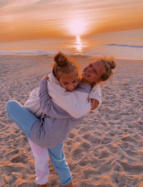 two girls hugging on the beach at sunset