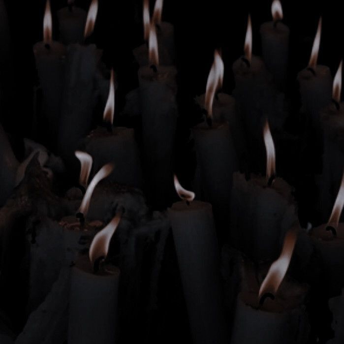 many lit candles in the dark with white flames