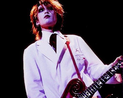 a man in white shirt and tie holding a guitar