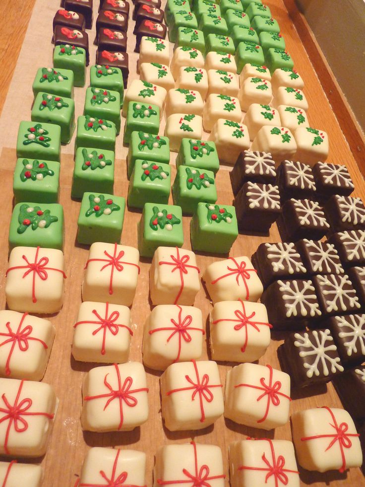 many different types of decorated chocolates on a wooden table with bows and snowflakes