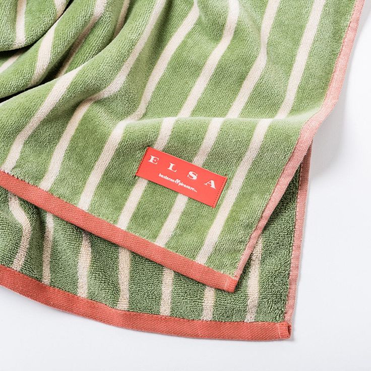 a green and white striped towel laying on top of a table next to a red tag