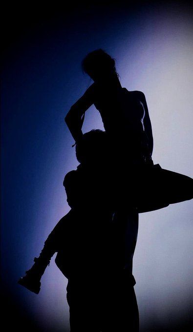 two people are silhouetted against a blue background, one is holding the other's head