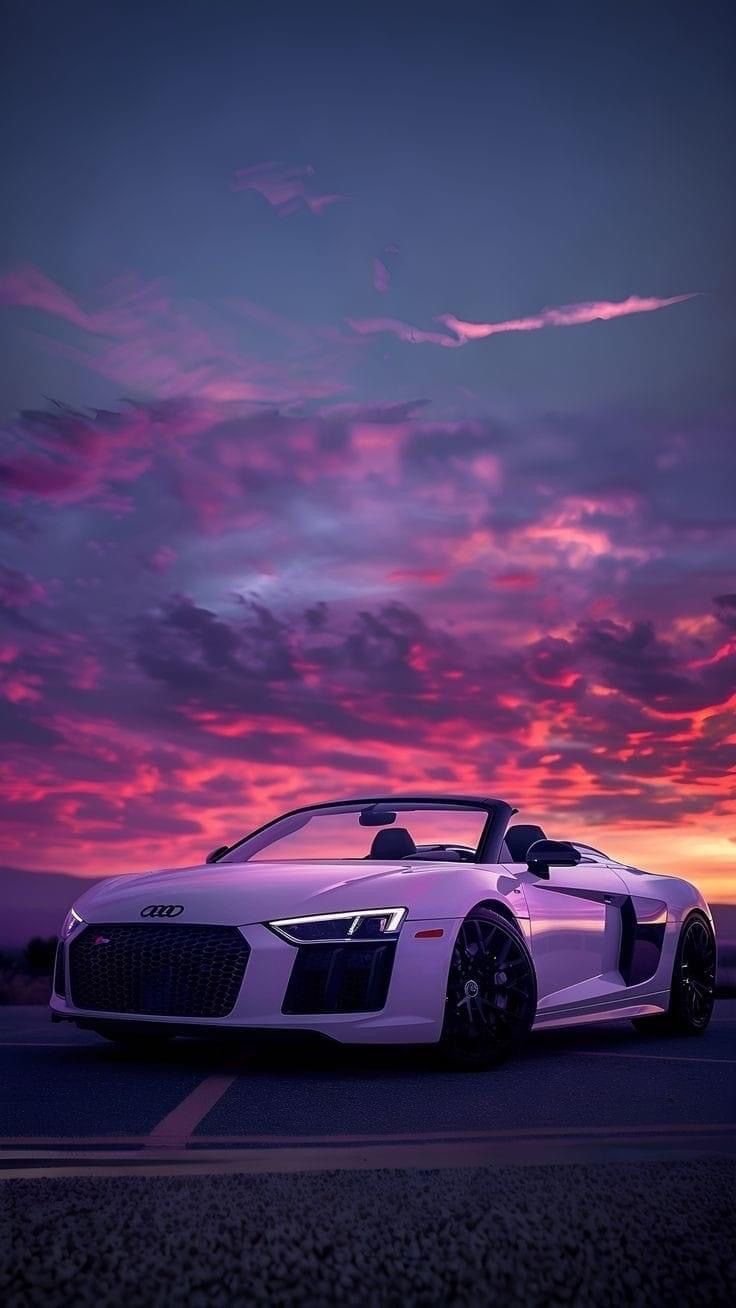 a white sports car parked in front of a sunset