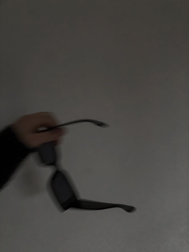 a hand holding an object in the air with it's shadow on the wall