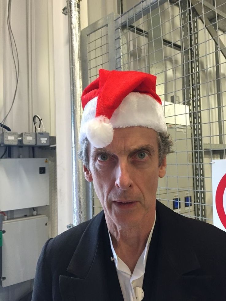 a man wearing a santa hat standing in front of a sign