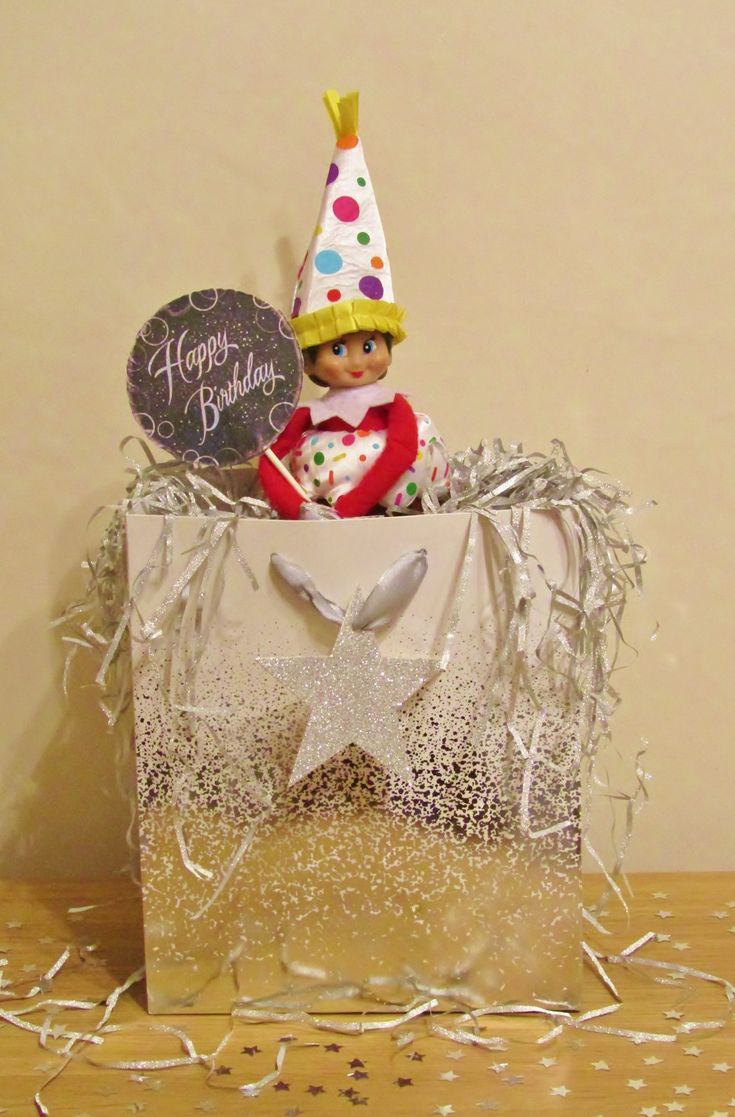 an elf in a birthday hat sitting on top of a bag with confetti