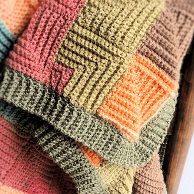 multicolored knitted blanket laying on top of each other in a wooden chair