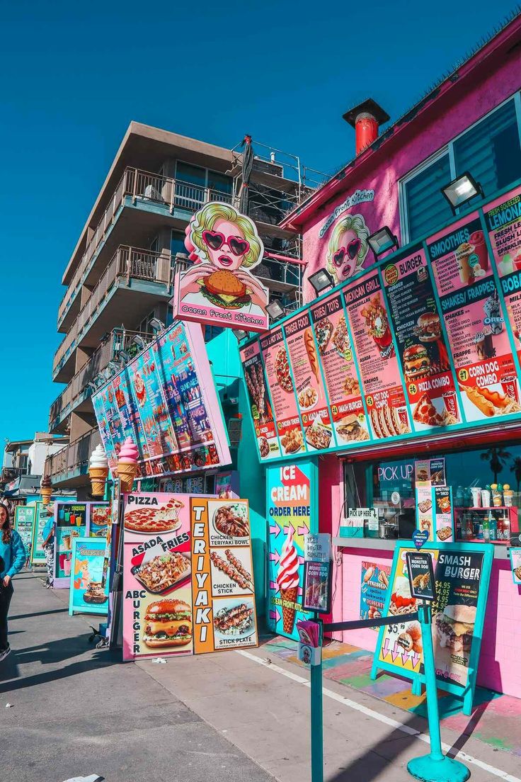 a street scene with people walking around and colorful food stands on the side of the road