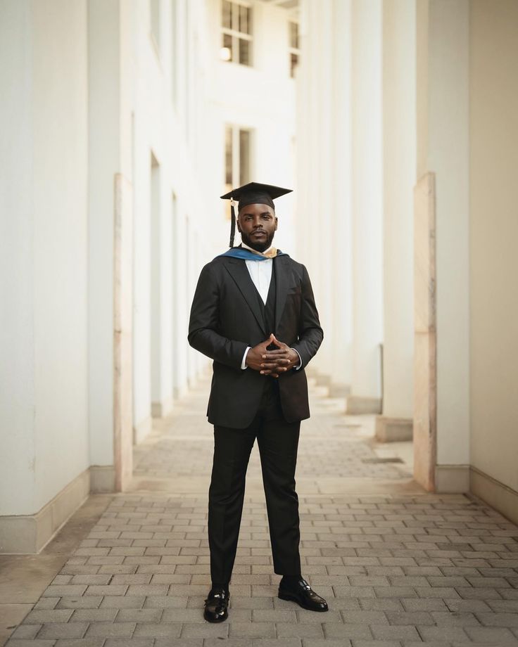 a man in a suit and tie is posing for a photo with his graduation cap on